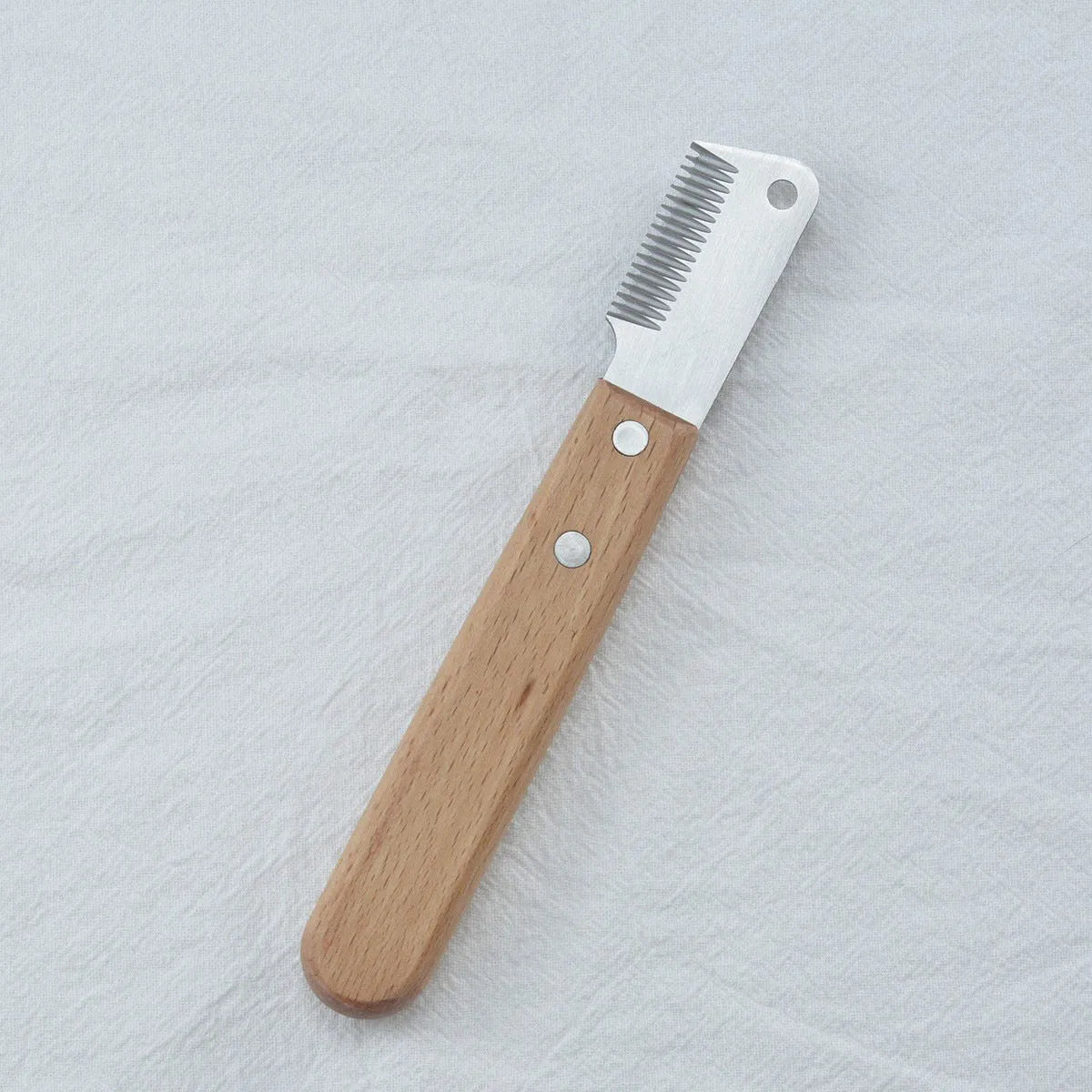 Dog stripping comb grooming tool with wood handle and metal blade for removing hair.