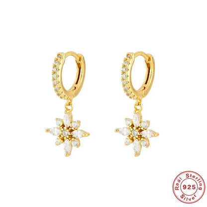 A pair of geometric snowflake pendant earrings in sterling silver with cubic zirconia stones, on a white background.