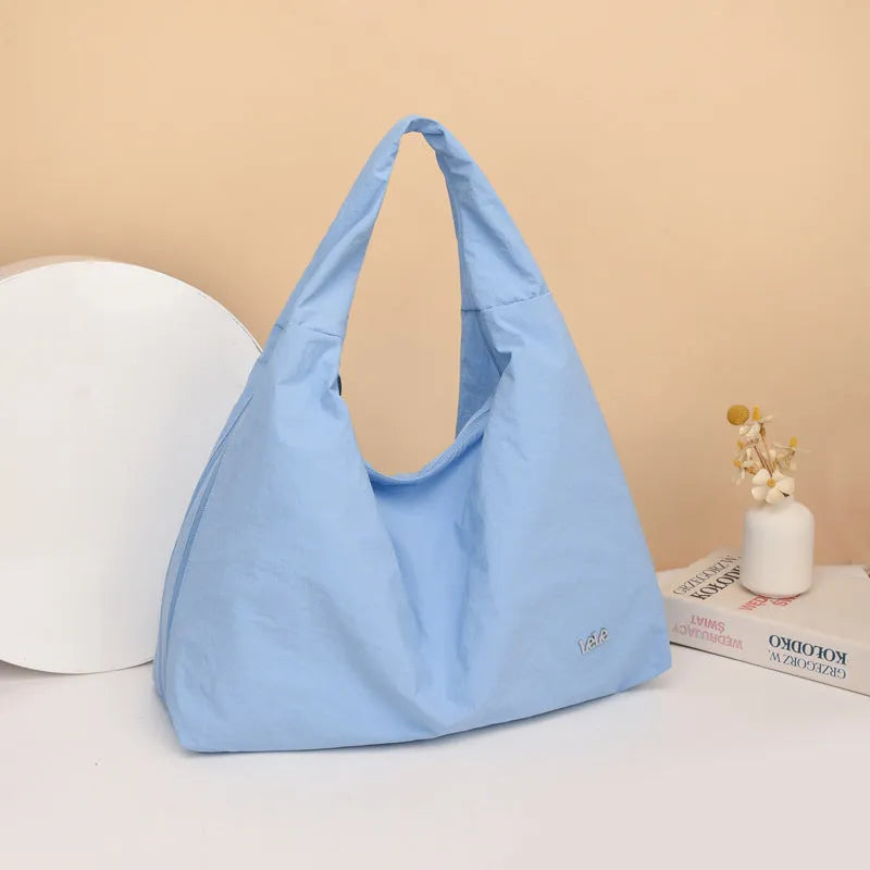 A soft nylon underarm bag with a heart-shaped design in blue, shown worn crossbody.