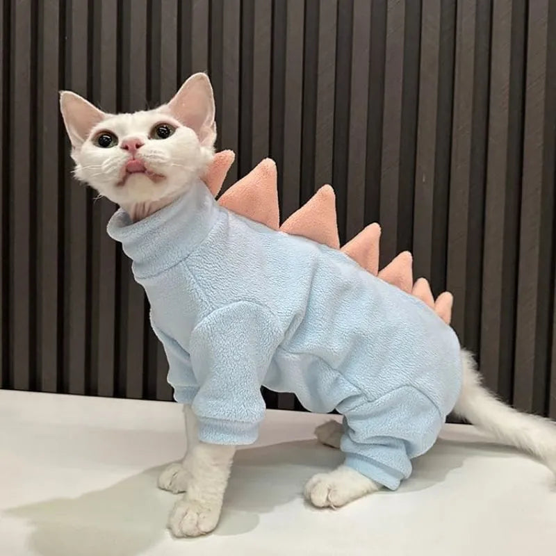 Sphynx cat wearing green dinosaur costume with tail and spikes
