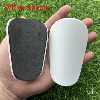 Extra small 8x5cm black and white plastic football shin guards for junior players.
