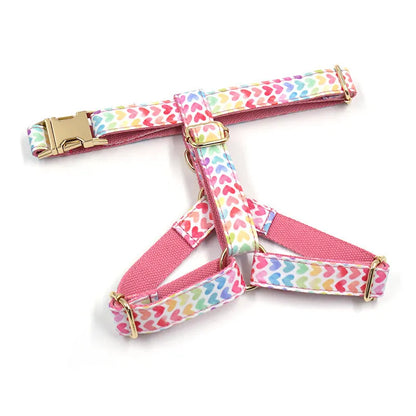 Pink dog harness with gold buckle and heart-shaped stones on a chest and back strap.