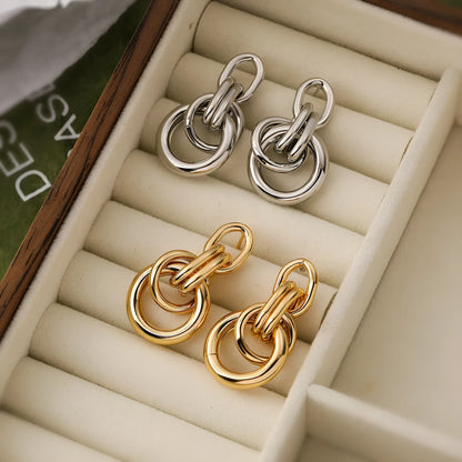 A pair of gold-coloured geometric drop earrings with irregular shapes, made from copper.