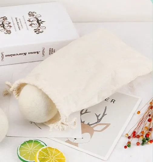 A 100% wool drying ball for laundry next to a plain cotton storage bag on a background.