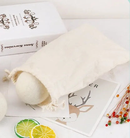 A 100% wool drying ball for laundry next to a plain cotton storage bag on a background.