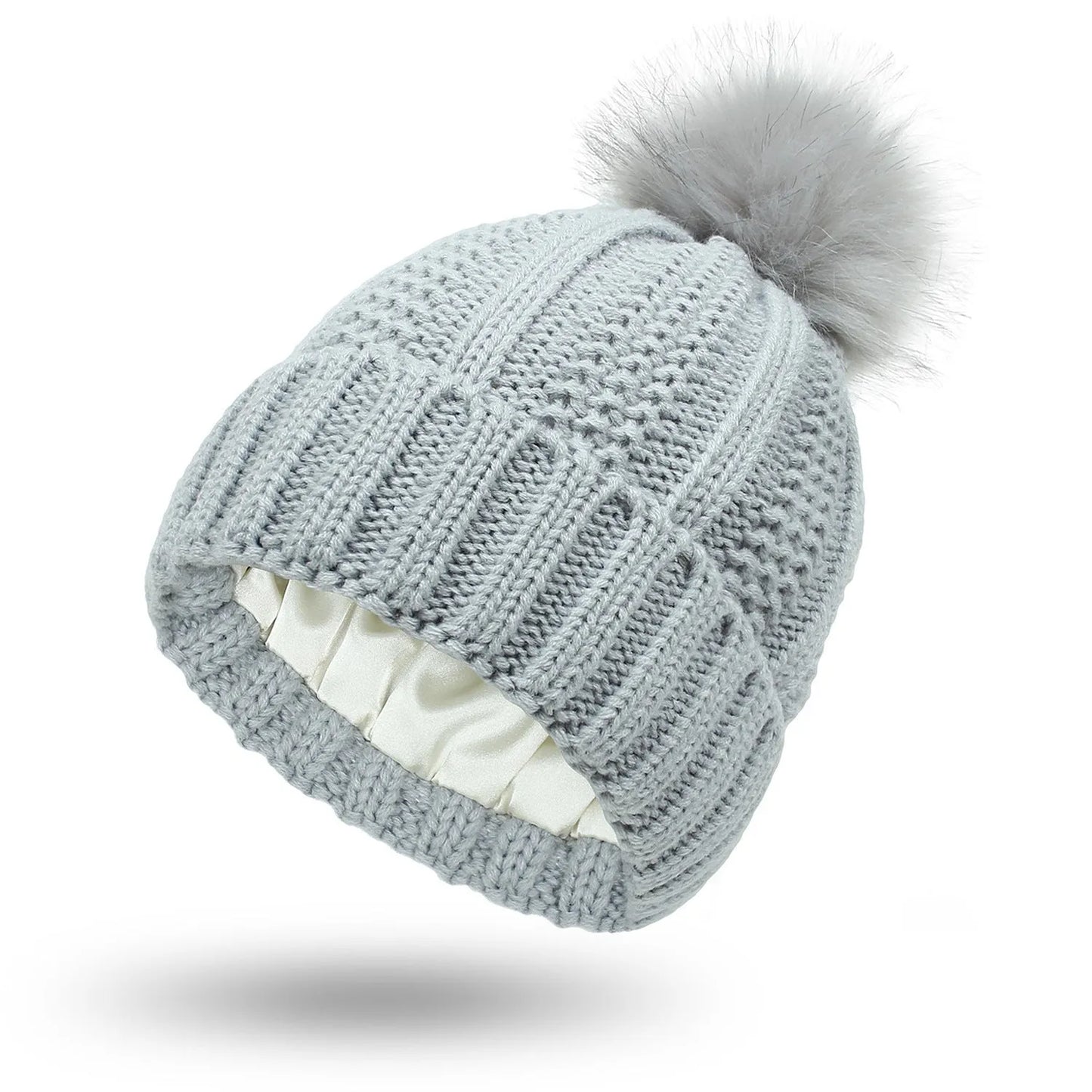 Woman wearing a wine red wool beanie hat with a faux fur pom pom and satin lining.