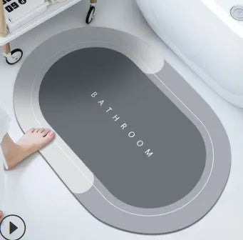 Oval diatomite bathroom floor mat in blue with natural rubber non-slip backing on tiled floor.