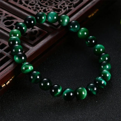 Green tiger's eye stone bracelet with geometric beads on a wrist.