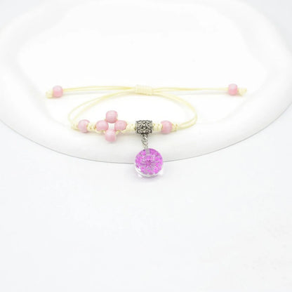 Close-up of a hand-woven bracelet with a large 1.4cm glass bead containing colourful dried flowers.