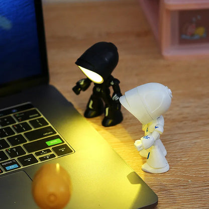 Mini mecha robot hero LED night light with adjustable arms on a desk.