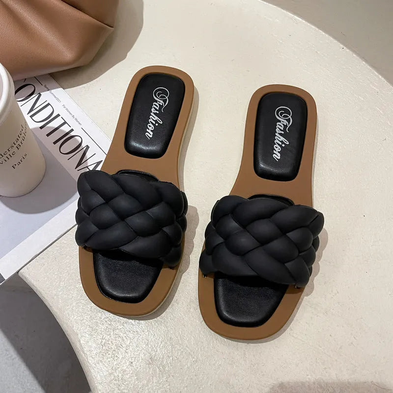 Women's white PVC beach sandals with a thick, patterned sole on a sandy background.