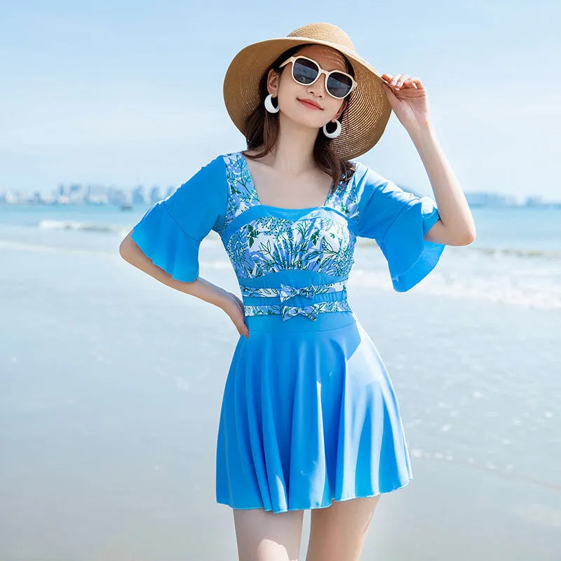 Women's green and blue seaside print one-piece swimsuit on hanger.