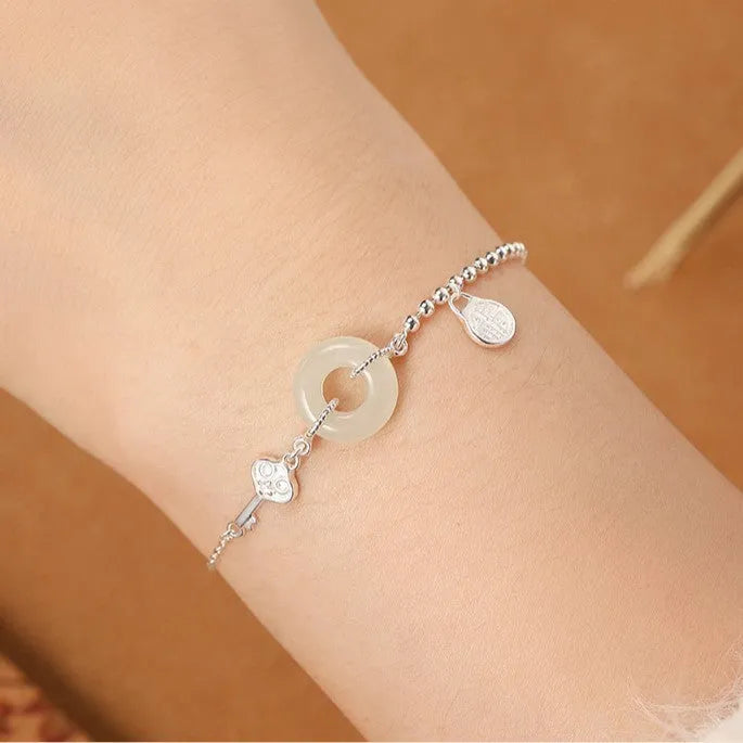Silver women's bracelet with Hetian jade stones and a geometric peace buckle charm.