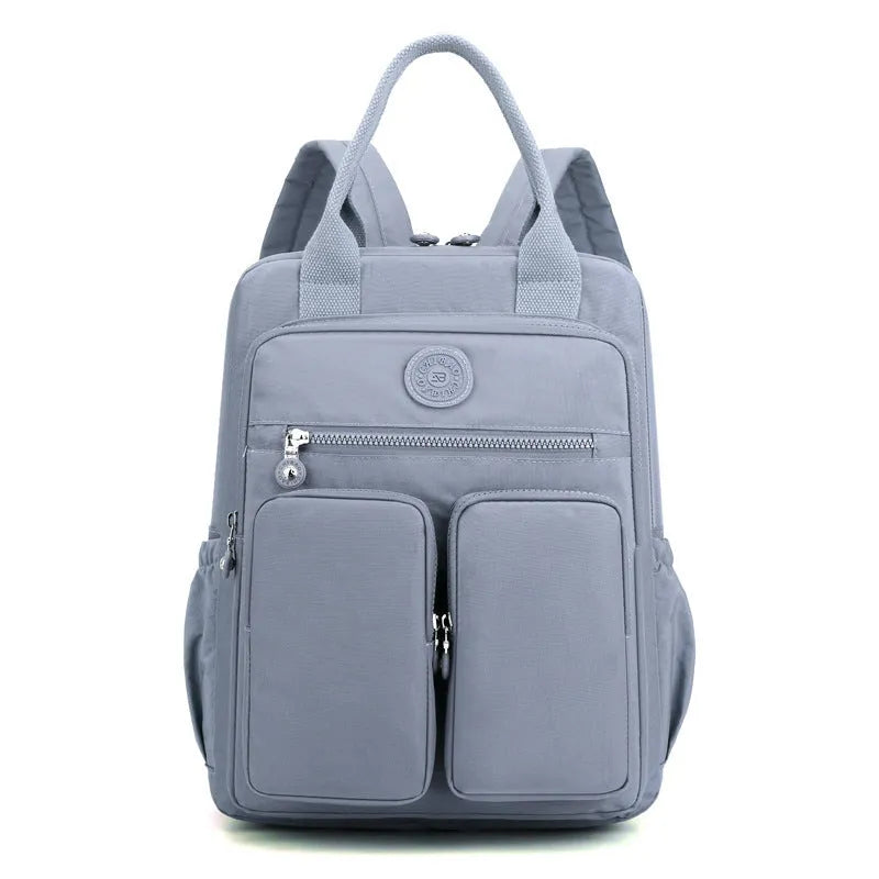 Women's waterproof nylon travel backpack in grey, showing front external pocket and organisational interior.