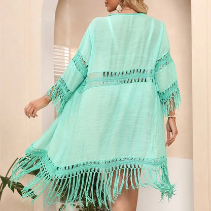 Yellow hand-crocheted acrylic beach cover-up cardigan with tassels, laid flat on a sandy background.