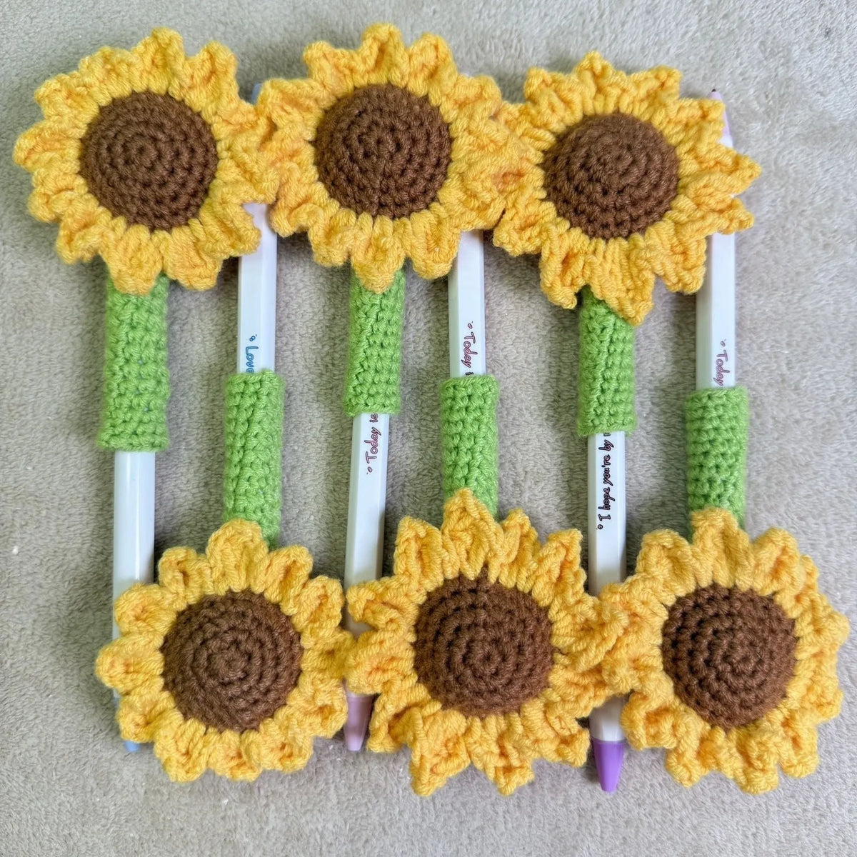 Hand-woven yellow and brown sunflower pen cover holding a pen.