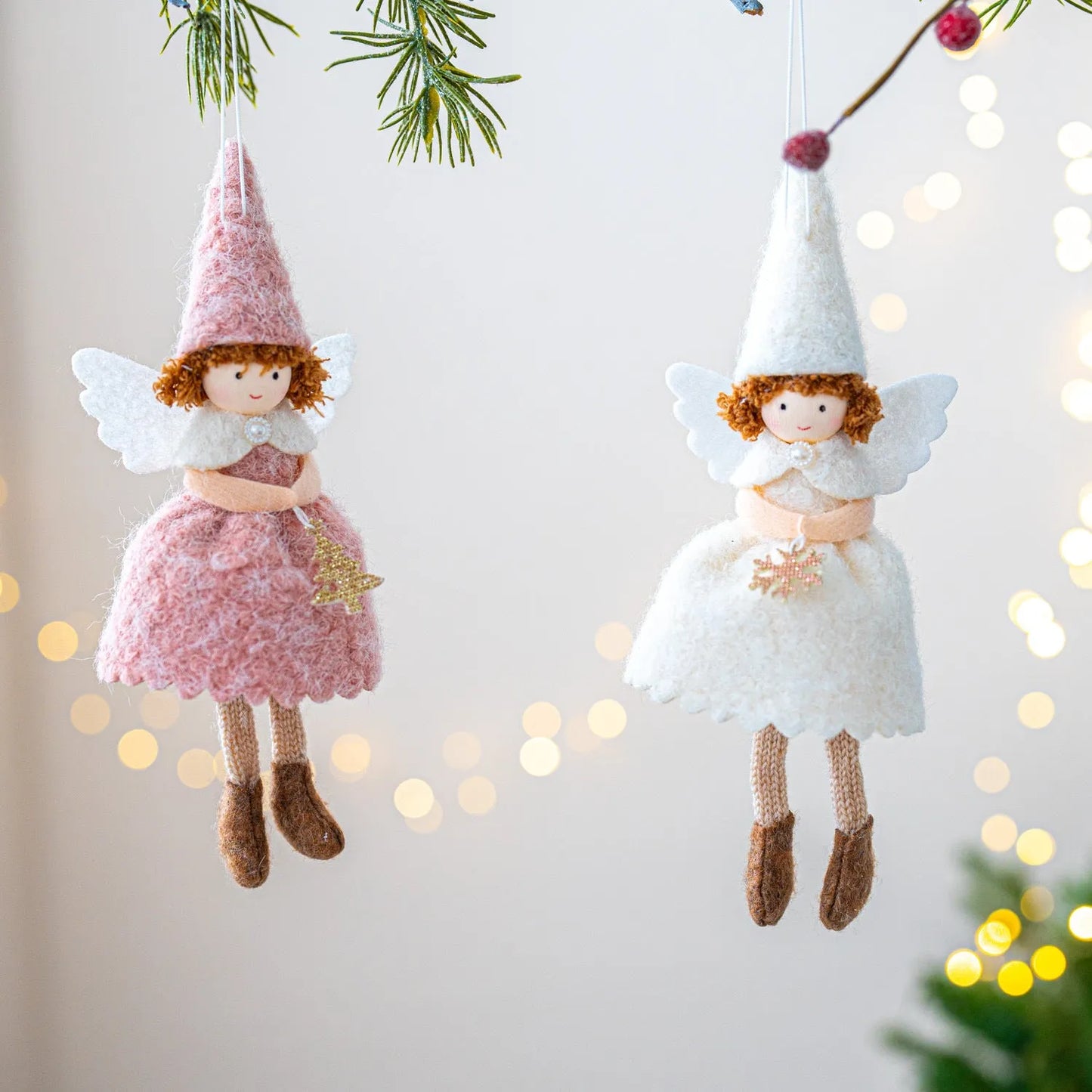 White and pink cloth felt Christmas angel skirt pendant ornament on a tree branch.