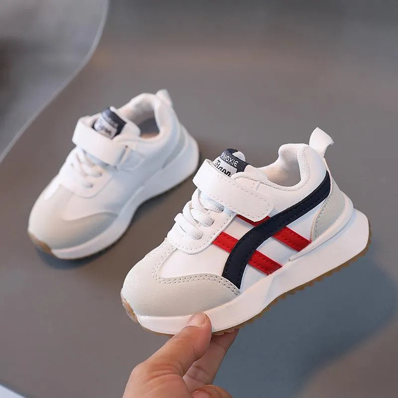 Children's white synthetic leather sneaker with Velcro strap on a non-slip rubber sole.
