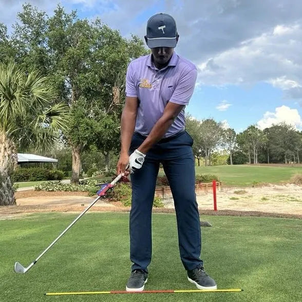 Plastic golf swing plane simulator training aid on a practice mat.