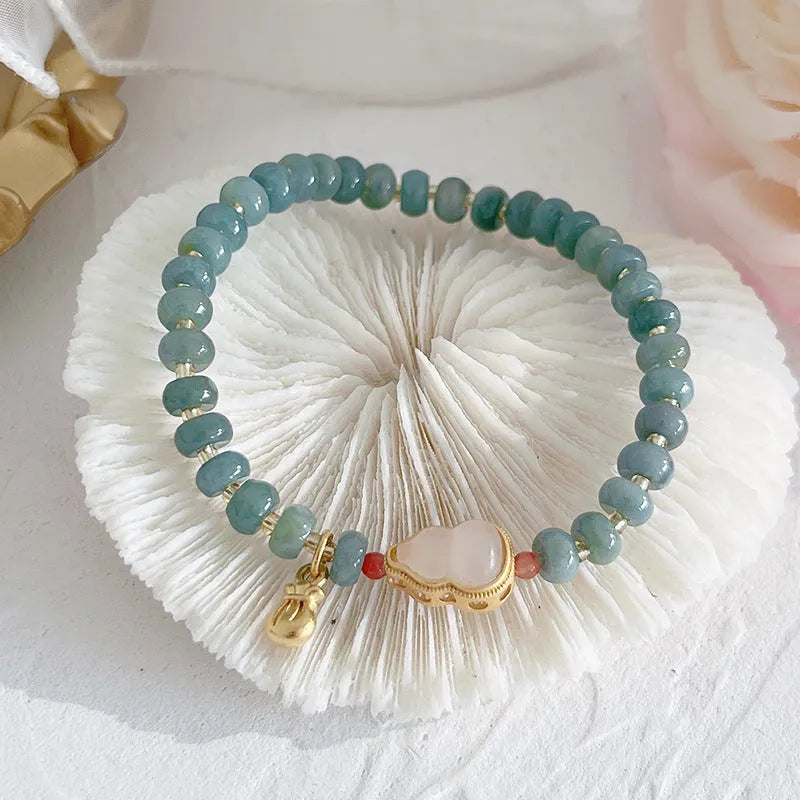 Simple blue jade bracelet with gourd charm, peace buckle, and adjustable cord on woman's wrist