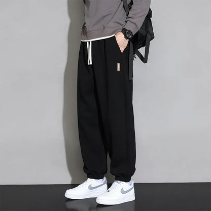 Man wearing loose grey sports trousers with an elasticated drawstring waistband.