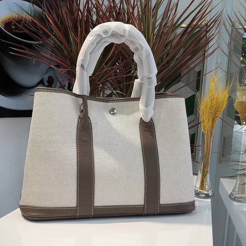 Canvas and leather tote bag in bucket shape with crossbody strap, shown in black, brown, gray or red colour options
