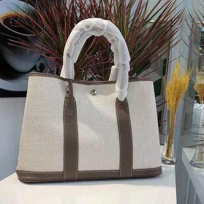 Canvas and leather tote bag in bucket shape with crossbody strap, shown in black, brown, gray or red colour options
