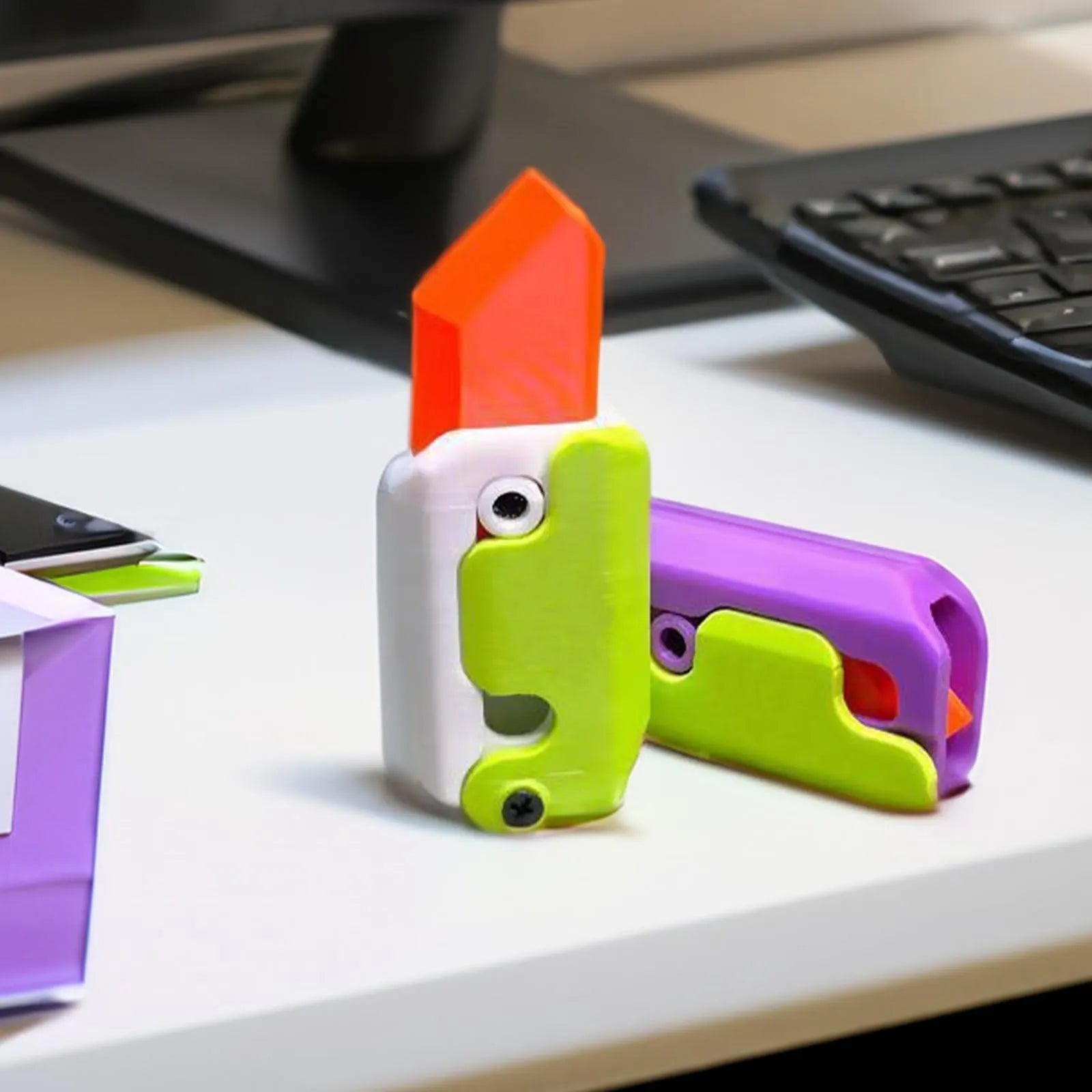 3D printed plastic carrot fidget knife with retractable blade, shown in orange and green colour scheme.