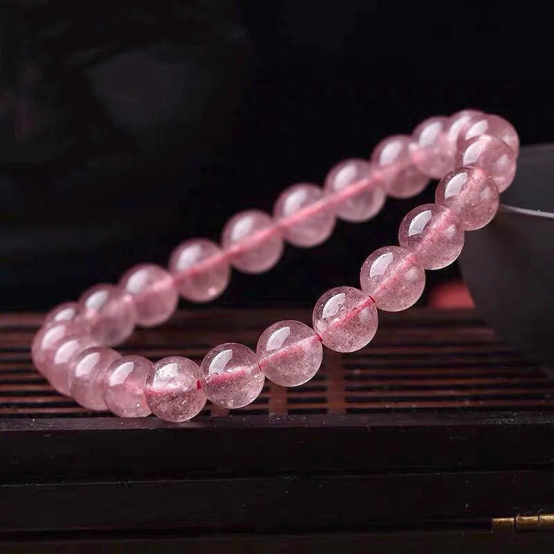 A women's bracelet made of polished strawberry quartz crystal beads in one of three size options.