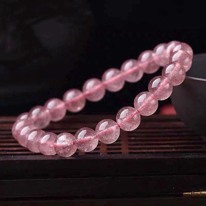 A women's bracelet made of polished strawberry quartz crystal beads in one of three size options.