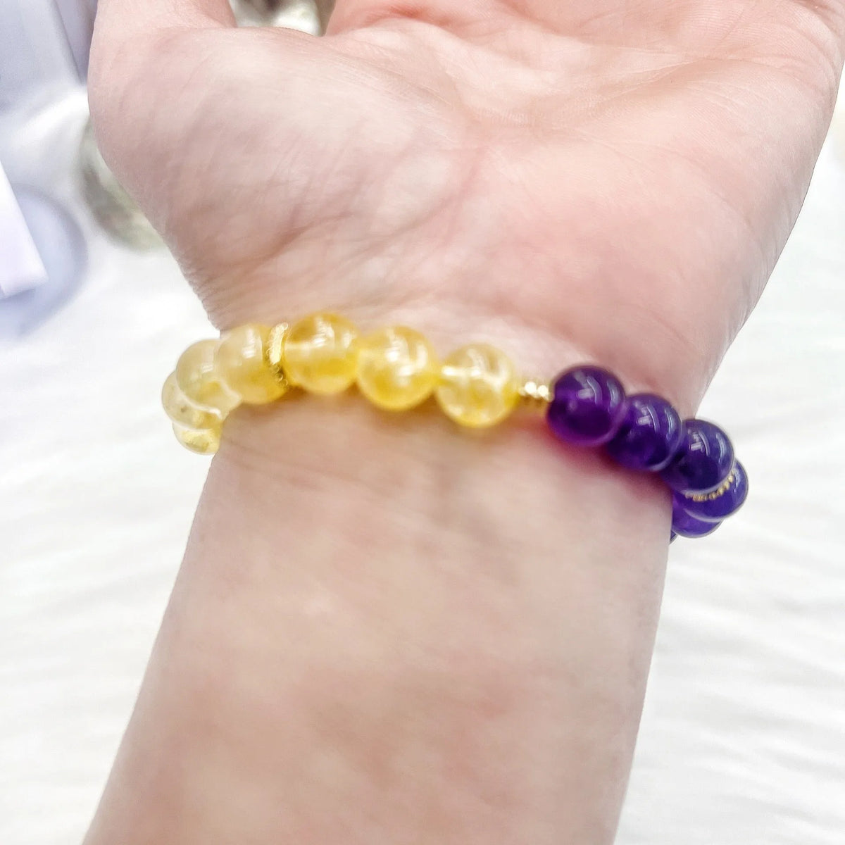 Handmade women's bracelet with yellow and purple amethyst crystals on wrist.