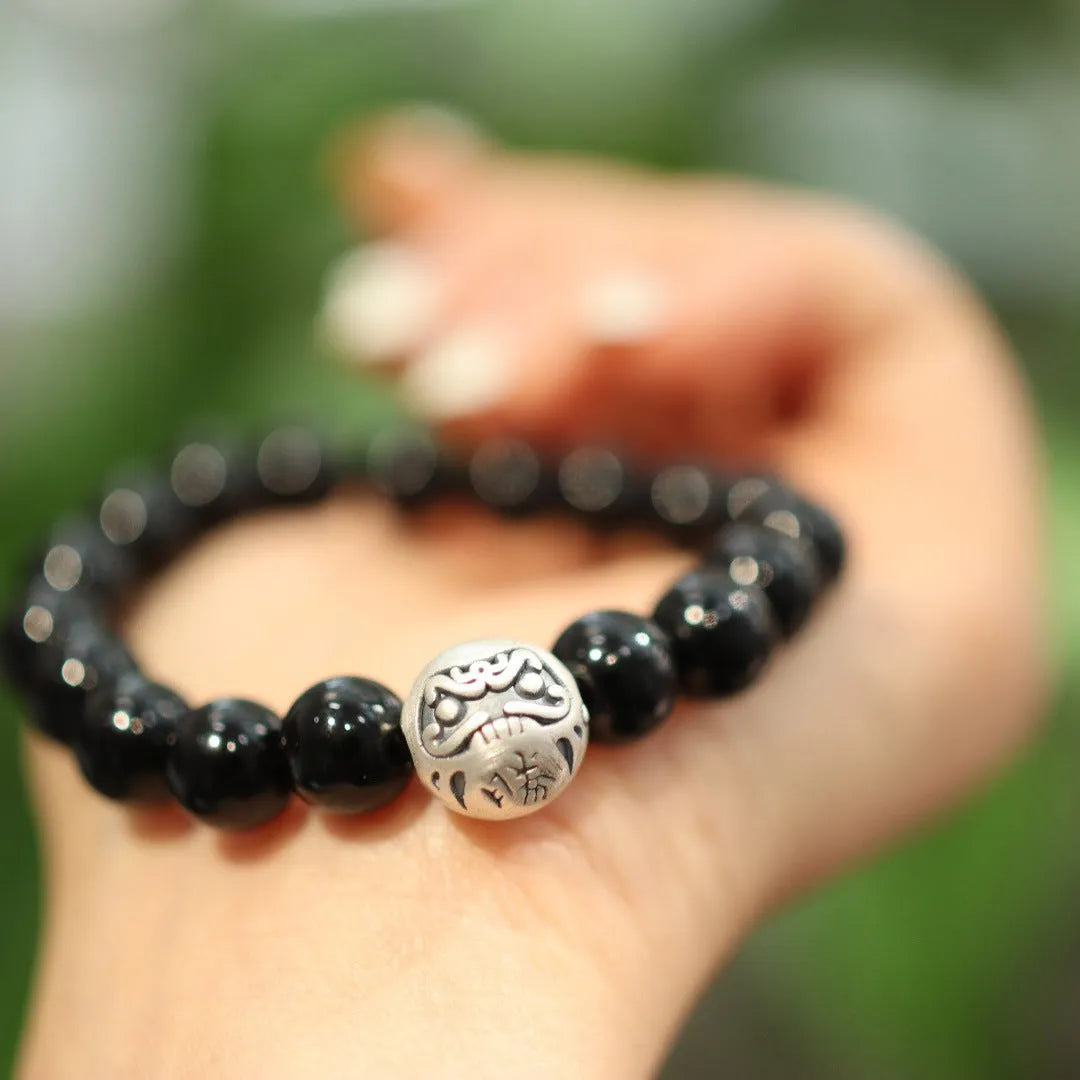 Close-up of a women's black agate bracelet with 10mm beads and a sterling silver clasp on a wrist.