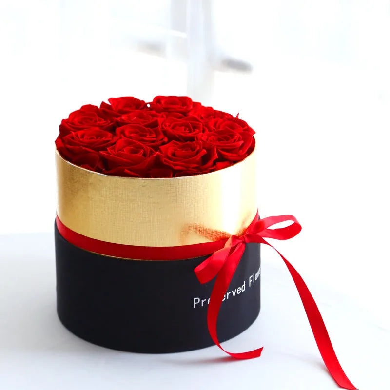 Luxury gift box containing an arrangement of preserved red eternal roses on a dark background.