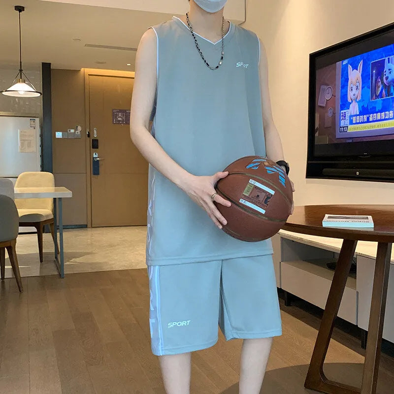 Man wearing a grey sleeveless basketball vest and matching shorts for sports.