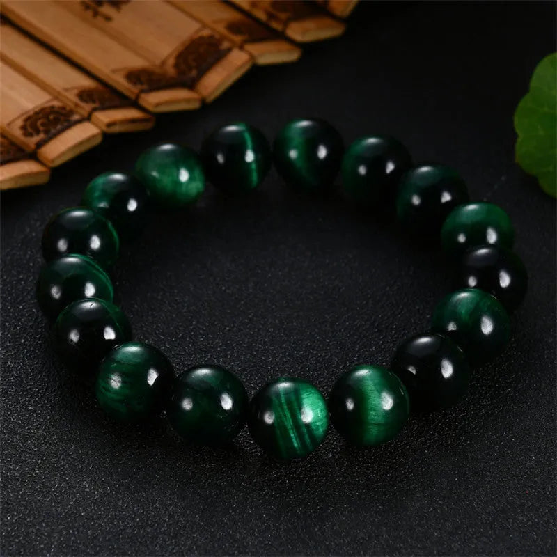 Green tiger's eye stone bracelet with geometric beads on a wrist.