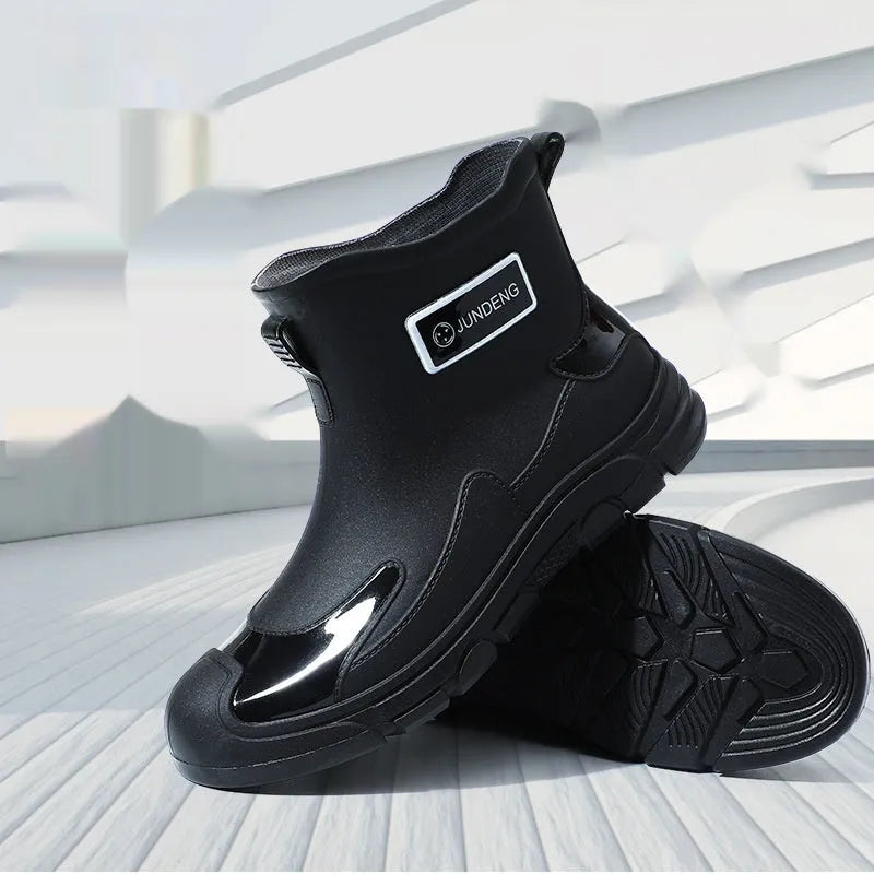 Minimalist black PVC waterproof wading boots with flat heel and round toe on a neutral background.
