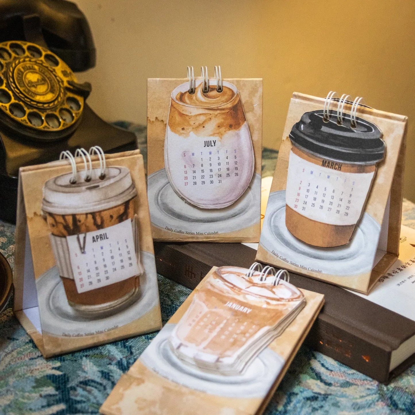 Set of four different themed 2025 mini paper desk calendars on a desk.
