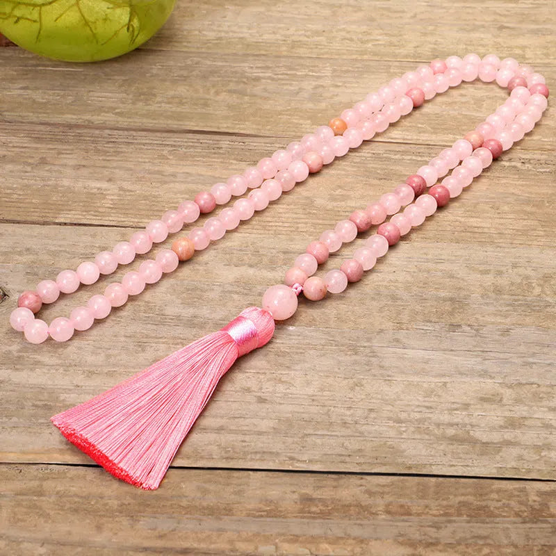 Natural stone bead necklace and bracelet set with a long fringe tassel pendant on a table.