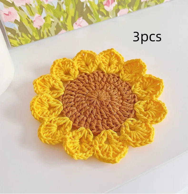 Hand-woven circular wool coaster with a flower pattern, part of a set for table protection.
