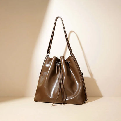 Brown genuine leather retro-style bucket bag with a single shoulder strap showing internal zipped compartments.