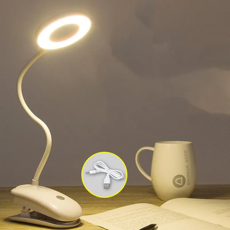A modern white clip-on rechargeable desk lamp with a touch-sensitive switch and a plastic shade.