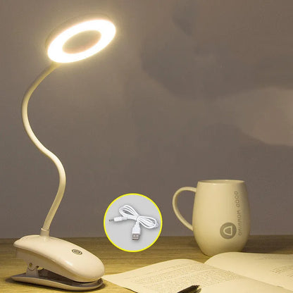 A modern white clip-on rechargeable desk lamp with a touch-sensitive switch and a plastic shade.