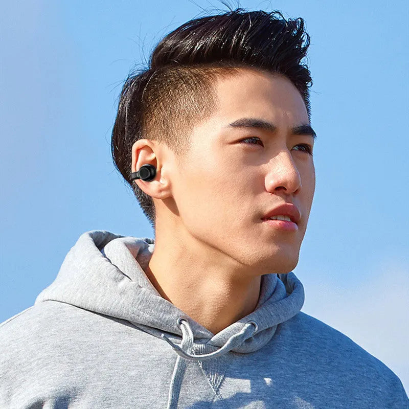 Black wireless Bluetooth clip-on earphones with bone conduction technology on a white background.