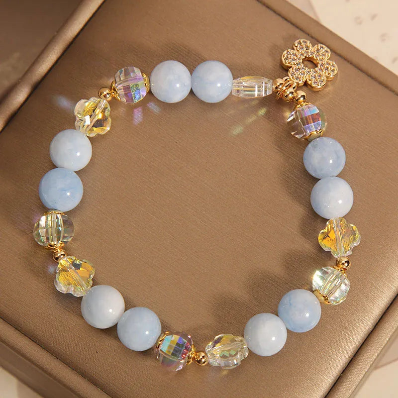 Women's aquamarine crystal bracelet with four-leaf clover charm and pearl details on wrist