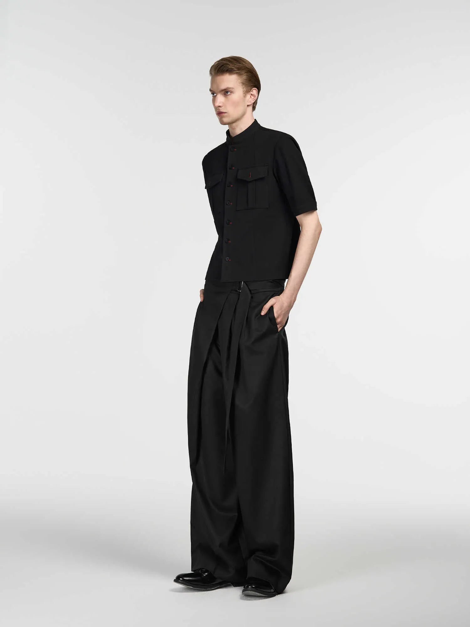 Black straight-leg trousers with single front pleat and adjustable waistband on a hanger