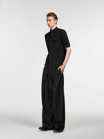 Black straight-leg trousers with single front pleat and adjustable waistband on a hanger