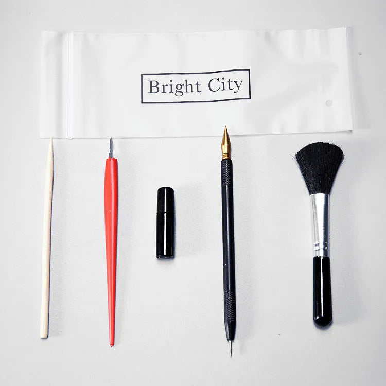 Diamond painting repair tool set with metal scraper pen, bottle of adhesive liquid, soft brush, and bamboo stick on a craft table