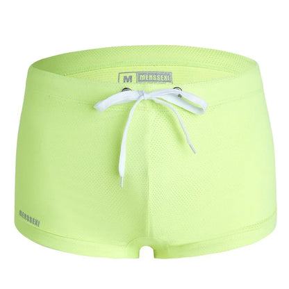 Men's low waist swim trunks in stretch nylon on a man, showing elastic waistband and boxer-style cut.