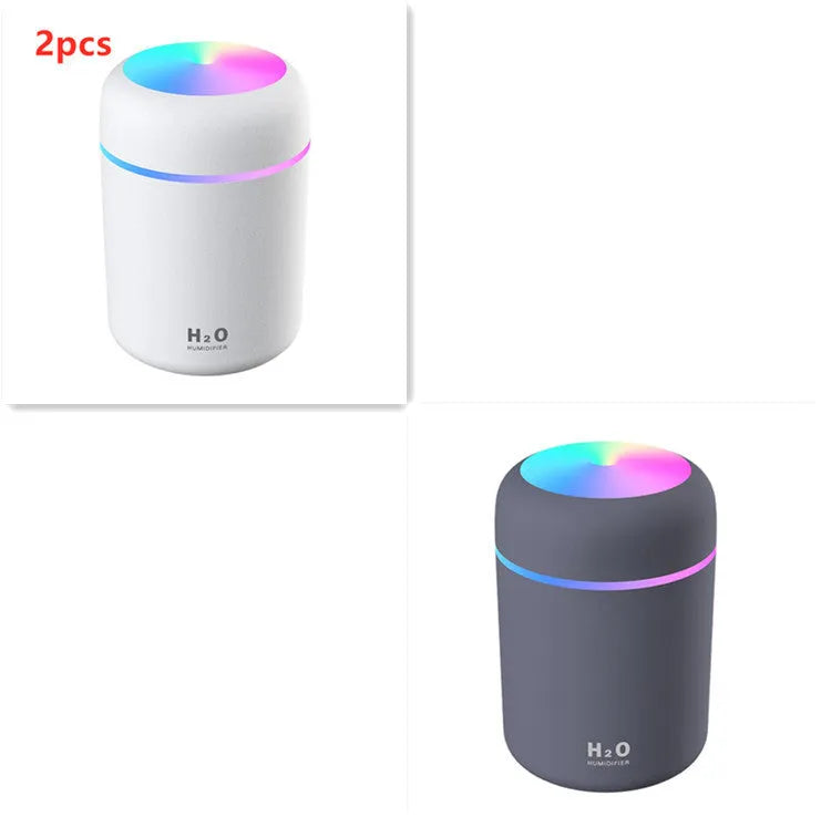 Pink USB desktop humidifier with LED lights and water tank on wooden desk
