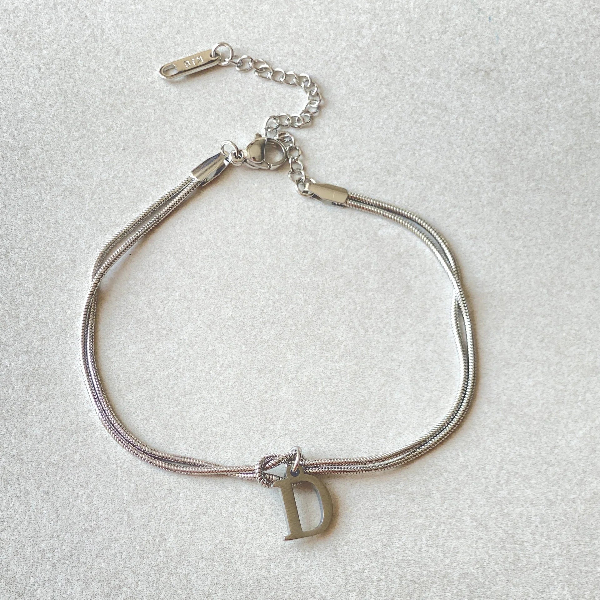 Elegant letter charm bracelets for women in gold and silver tones, featuring a delicate snake chain design and personalised letter charms.